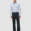 En mann iført en Elevated Shirt Slim Classic Blue Striped – en lyseblå stripete skjorte med knapper – og mørke bukser.