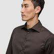 En mann kledd i en mørkebrun Elevated Shirt Slim Dark Brown-skjorte i Pima-bomull med smal passform og knapper.