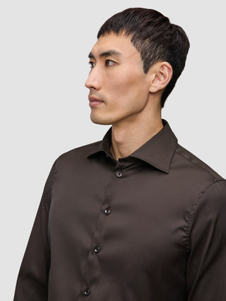 En mann kledd i en mørkebrun Elevated Shirt Slim Dark Brown-skjorte i Pima-bomull med smal passform og knapper.