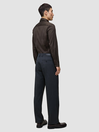 Bakfra-bilde av en mann som har på seg en mørkebrun Elevated Shirt Slim, stappet inn i mørkegrå bukser og mørke skinnsko.