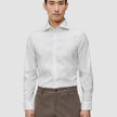 En mann kledd i en Elevated Shirt White Slim i Pima-bomull med spredt krage og brune bukser.