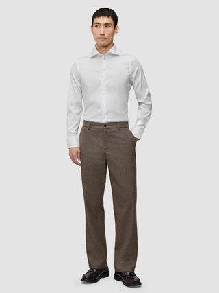 En mann kledd i en hvit, smal Elevated Shirt i Pima-bomull og brune bukser.