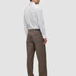 En mann sett bakfra har på seg en hvit, smal Elevated Shirt som er stappet ned i brune bukser og mørke skinnloafers.