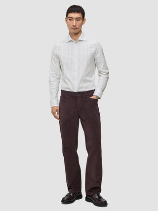 En mann i en Elevated Shirt Slim med lysegrå striper, mørke bukser og mørke loafers.