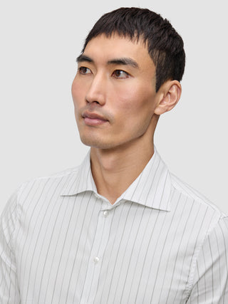 En mann kledd i en Elevated Shirt Slim Light Grey Striped, en lysegrå, vertikalt stripete Pima-bomullsskjorte med knapper.