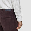 En person som har på seg en Elevated Shirt Slim Light Grey Striped, som er stappet inn i mørkebrune corduroybukser.