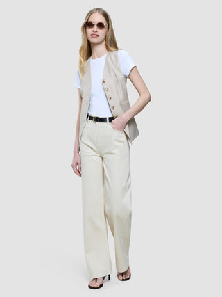 En kvinne i en beige vest og hvit T-skjorte, kombinert med «Women’s Relaxed Jeans Off White» og ovale solbriller.