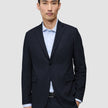 En mann i en Motion Blazer Regular i fargen Midnight Blue over en lyseblå stripete skjorte.