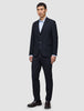 En mann i en Motion Blazer Regular-dress i midnattsblått med matchende bukser, en lyseblå skjorte og mørke loafers.