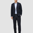 En mann kledd i en Motion Blazer Slim i fargen Midnight Blue, matchende bukser, en lyseblå skjorte og mørke loafers med 360°-stretch.