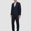 En mann i en Motion Blazer Slim-jakke i midnattsblått, matchende bukser, en lyseblå skjorte og brune loafers.