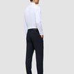 En mann i hvit skjorte og en Midnight Blue Motion Suit Pants Regular-bukse står med ryggen til kameraet.