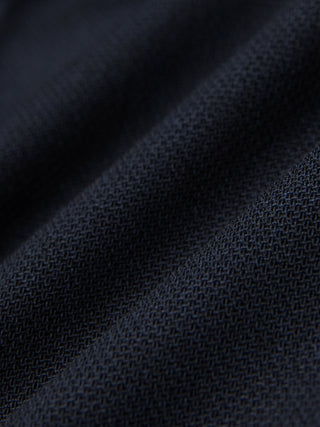Nærbilde av brettede Motion Suit-bukser i Regular-modell, fargen Midnight Blue, med mørkeblått strukturert stoff og 360°-stretch.
