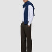 En mann i en hvit skjorte med smale striper, en marineblå genser og Motion Suit Pants Relaxed Cognac med 360°-stretch.