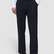 En person som har på seg Motion Suit-bukser i modell Relaxed i fargen Midnight Blue, en hvit skjorte med knapper og mørke loafers.