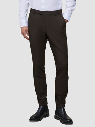 Mørkebrune Motion-dressbukser i slim fit-modell, Slim Cognac, kombinert med en hvit skjorte med knapper og svarte lærstøvler.