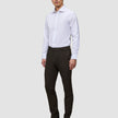 En mann har på seg en hvit skjorte, Motion Suit Pants Slim Cognac og svarte støvler i et rent, skandinavisk design.