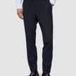 Motion Suit Pants Slim – Midnattsblå dressbukser i slim fit, kombinert med en hvit skjorte med knapper og brune loafers.