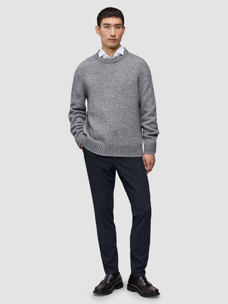 En mann i en grå genser, hvit skjorte med krage og Midnight Blue Motion Suit Pants Slim i skandinavisk design.