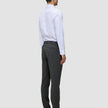 En mann i en hvit skjorte med knapper og Motion Suit-bukser i fargen Slim Pepper Grey, sett bakfra.