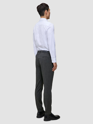 En mann i en hvit skjorte med knapper og Motion Suit-bukser i fargen Slim Pepper Grey, sett bakfra.