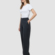 En kvinne iført en hvit T-skjorte og «Women Nara Pants Straight Grey Flint», med hånden i lommen.