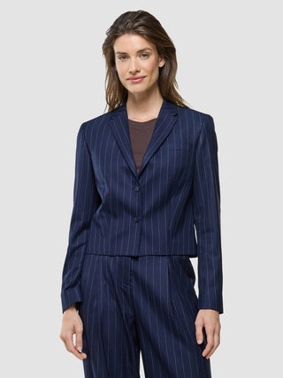 En kvinne har på seg en «Women Raina Short Blazer Night Sky Pinstripe» over en mørkebrun topp, noe som gjenspeiler et rent, skandinavisk design.