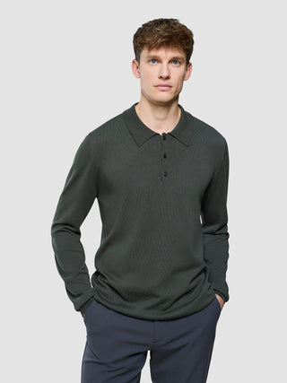 En mann iført en Seamless Core Knit langermet polo i fargen Green Night.