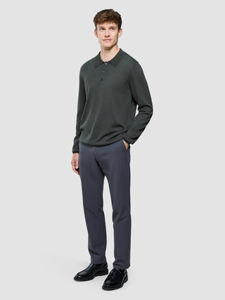 En mann kledd i en «Seamless Core Knit Long Sleeve Polo Green Night» og mørkegrå bukser.