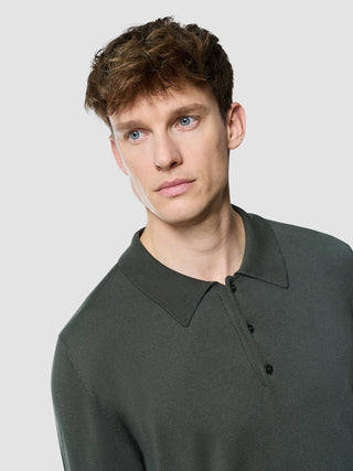 En mann iført en Seamless Core Knit langermet polo i fargen Green Night.