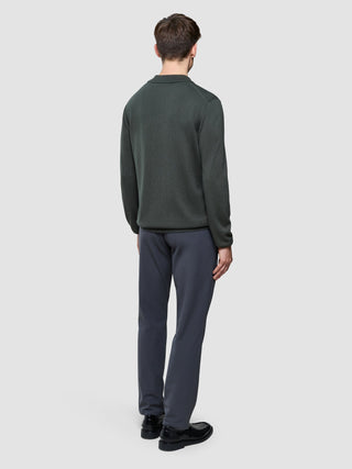En mann sett bakfra, kledd i en «Seamless Core Knit Long Sleeve Polo Green Night» og grå bukser.
