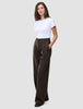 En person har på seg en hvit T-skjorte og Serene Pants Wide Walnut Herringbone – en buksemodell med høy midje, vide ben og nålestriper.