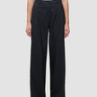 En person som har på seg de svarte Serene Pants Wide Black-buksene med plissering foran og en hvit T-skjorte i skandinavisk stil.