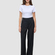 En kvinne iført en hvit T-skjorte og svarte Serene Pants Wide Black-bukser med høy midje og vide ben.