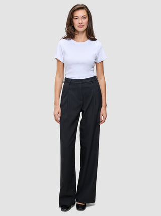 En kvinne iført en hvit T-skjorte og svarte Serene Pants Wide Black-bukser med høy midje og vide ben.