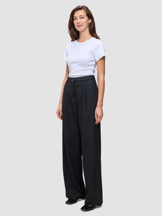 En kvinne iført en hvit T-skjorte og svarte Serene Pants Wide Black med høy midje.