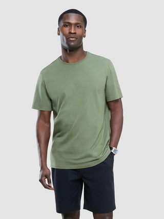 En mann kledd i en Supima-T-skjorte i fargen Clover Green og mørke shorts i et rent, skandinavisk design.