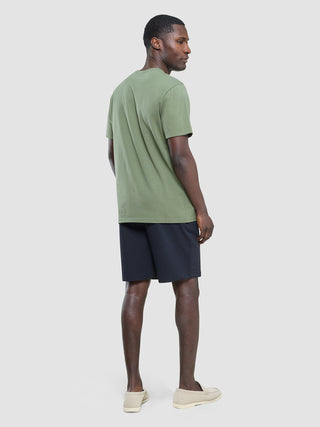 Baksiden av en mann i en Supima-T-skjorte i fargen «Clover Green», mørke shorts og lyse loafers i skandinavisk stil.