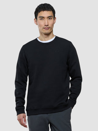 En mann som har på seg en svart sweatshirt med rund hals over en hvit T-skjorte.