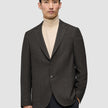 En mann som har på seg en Timeless Wool Blazer Slim i mørkebrun rutemønster over en beige turtleneck-genser.