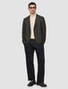 En person som har på seg en Timeless Wool Blazer Slim i mørkebrun rutemønster over en beige turtleneck og mørke bukser.