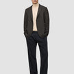 En person som har på seg en Timeless Wool Blazer Slim i mørkebrun rutemønster over en beige turtleneck og mørke bukser.