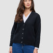 En kvinne som har på seg en svart, grovstrikket, myk ullcardigan for kvinner over en hvit skjorte med krage og blå jeans.