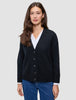 En person som har på seg en svart, tykk og myk strikket cardigan for kvinner over en hvit skjorte og blå jeans.