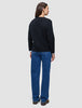 Sett bakfra har personen på seg en svart, tykk og myk ullstrikket cardigan for kvinner over en hvit skjorte og blå jeans.