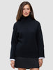 En person har på seg en svart, tykk og myk ullstrikket turtleneck for kvinner med vide ermer over en hvit skjorte.