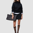 En kvinne har på seg en svart, tykk og myk ullstrikket turtleneck for kvinner over en hvit skjorte med krage, et svart skjørt, strømper og høyhælte sko.