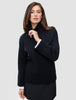 Kvinne iført en svart, tykk og myk ullstrikket turtleneck for kvinner, med hvite skjorte mansjetter som stikker frem.