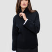 Kvinne iført en svart, tykk og myk ullstrikket turtleneck for kvinner, med hvite skjorte mansjetter som stikker frem.