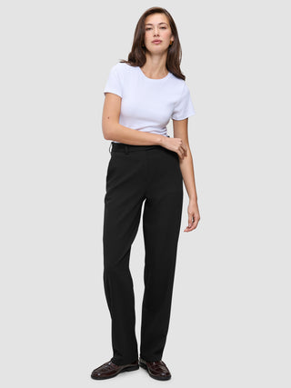 Kvinne kledd i en hvit T-skjorte, Women GO2-bukser i rett snitt i svart og mørke loafers i minimalistisk skandinavisk stil.